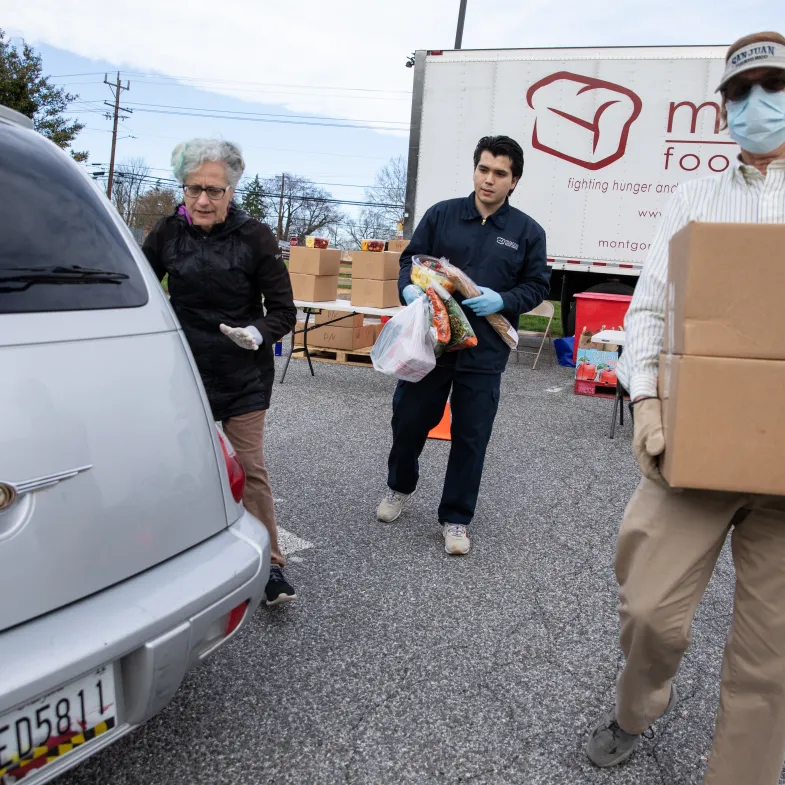 Volunteers load food into cars at a meal site in Maryland.
