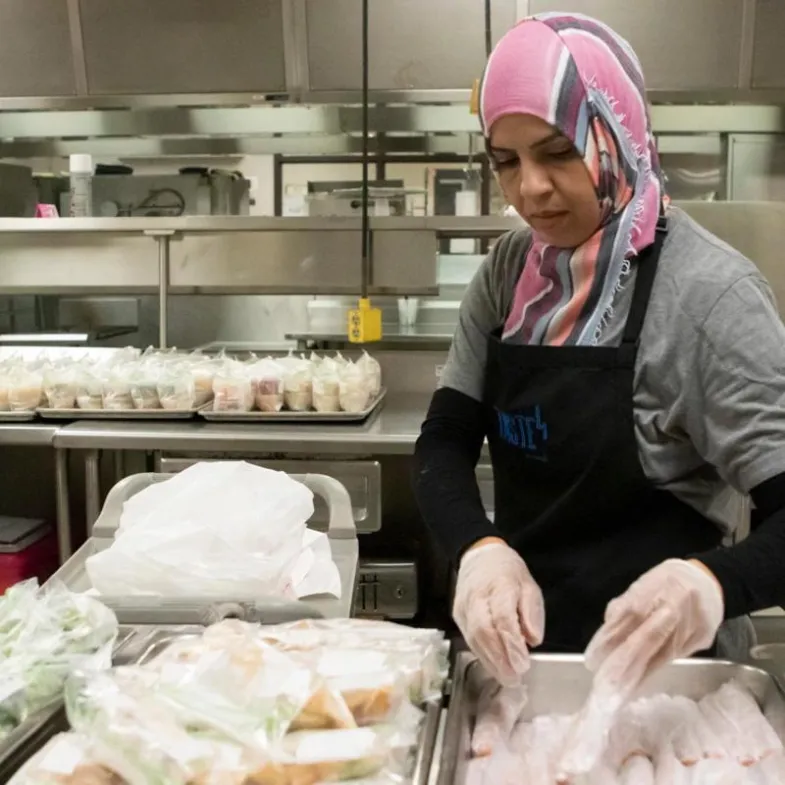 A woman prepares food for distribution at a summer meals site