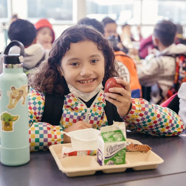 Girl eating apple in cafeteria