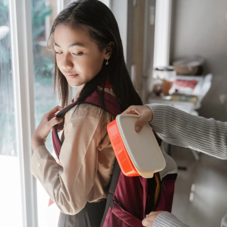 Parent placing lunch in child's backpack