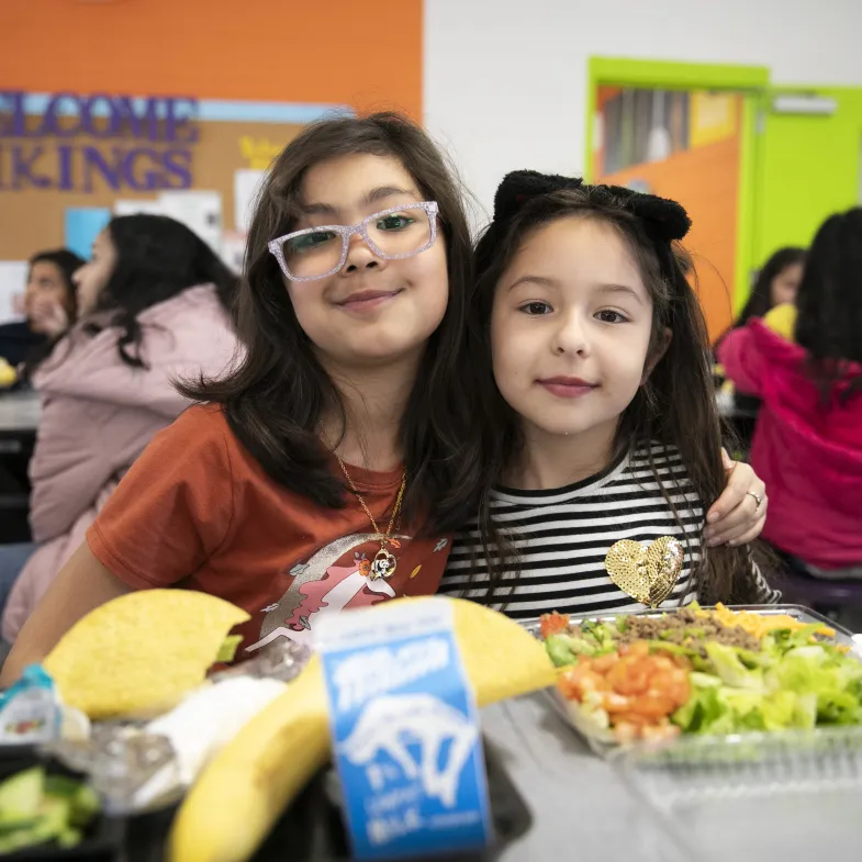 Two Latina girls posing in the cafeteria
