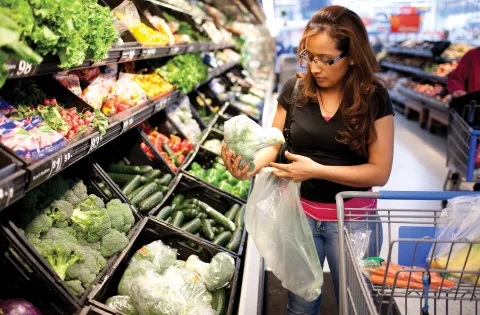 Woman getting broccoli from the produce isle