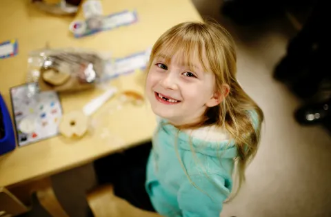 Little girl beaming and eating school breakfast