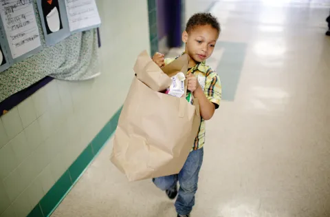 Little boy carrying trash away after classroom breakfast