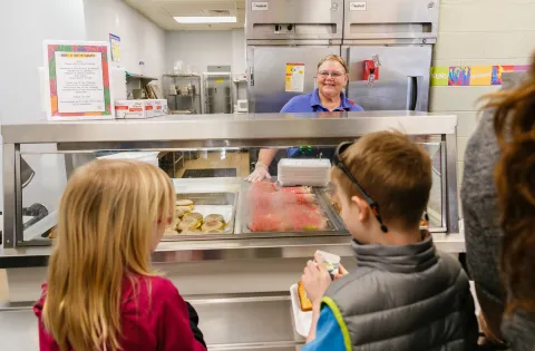 cafeteria worker smiling at kids