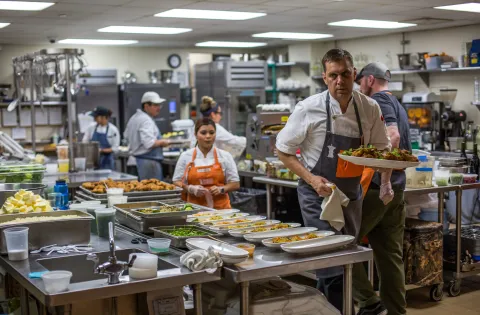 Chefs wearing No Kid Hungry aprons in a busy kitchen