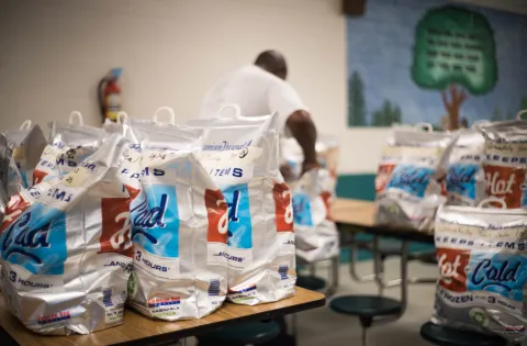 A man packs meal cooler bags for distribution.