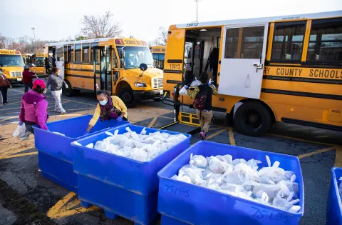 Manna Food Center staff and volunteers load school buses with food bags.