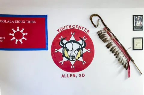 A flag and bison skull logo mark the white wall of the Lakota's Youth Center in Allen, South Dakota.