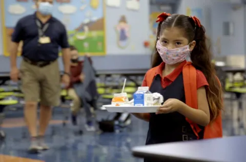 Little girl with mask holding food tray