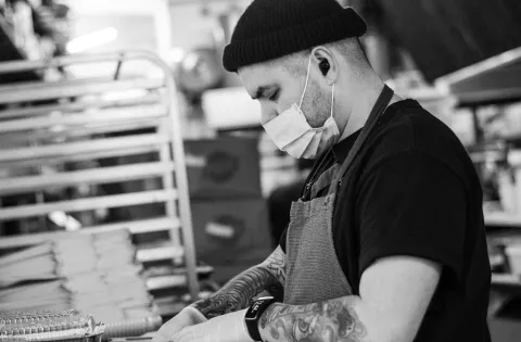 Black and white picture of chef with mask cooking a meal