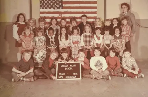 School picture of group of white kids with one Black kid