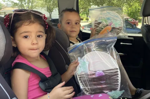 Kid in car with bags of crafts
