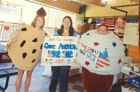WOman dressed as cookie, woman holding a sign and woman dressed as pancake
