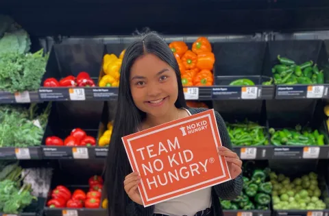 Youth Ambassador in front of fresh veggies