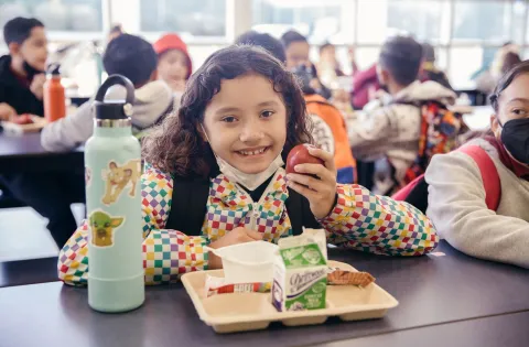 Girl eating apple in cafeteria