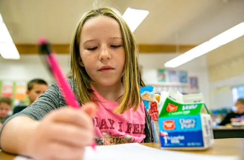 Girl at school writing with a pencil