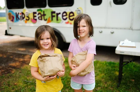 Girls holding paper bags full of food