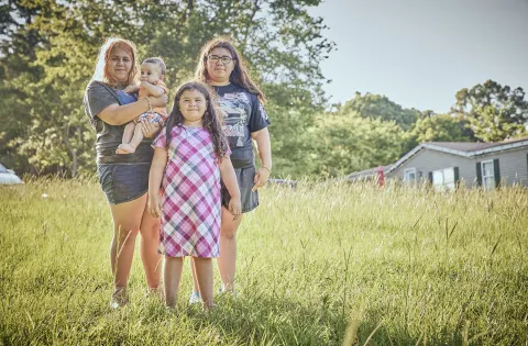 Three girls of different ages holding baby