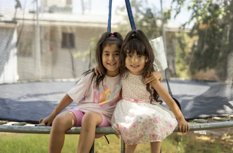 Two girls hugging on a trampoline