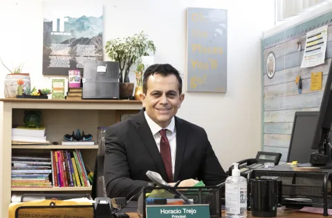 Principal Trejo sitting on desk
