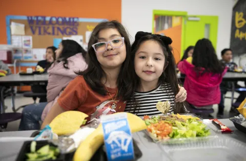 Two Latina girls posing in the cafeteria