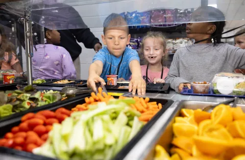 Kids in school cafeteria looking at cut fruit