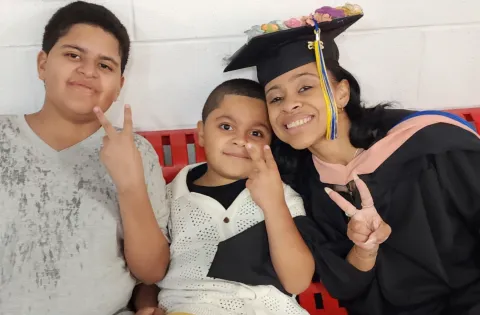 A mother wearing graduation gown with two kids