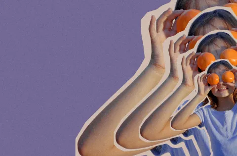 Girl holding tangerines up to her eyes