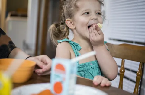 Little white girl eating a vegetable